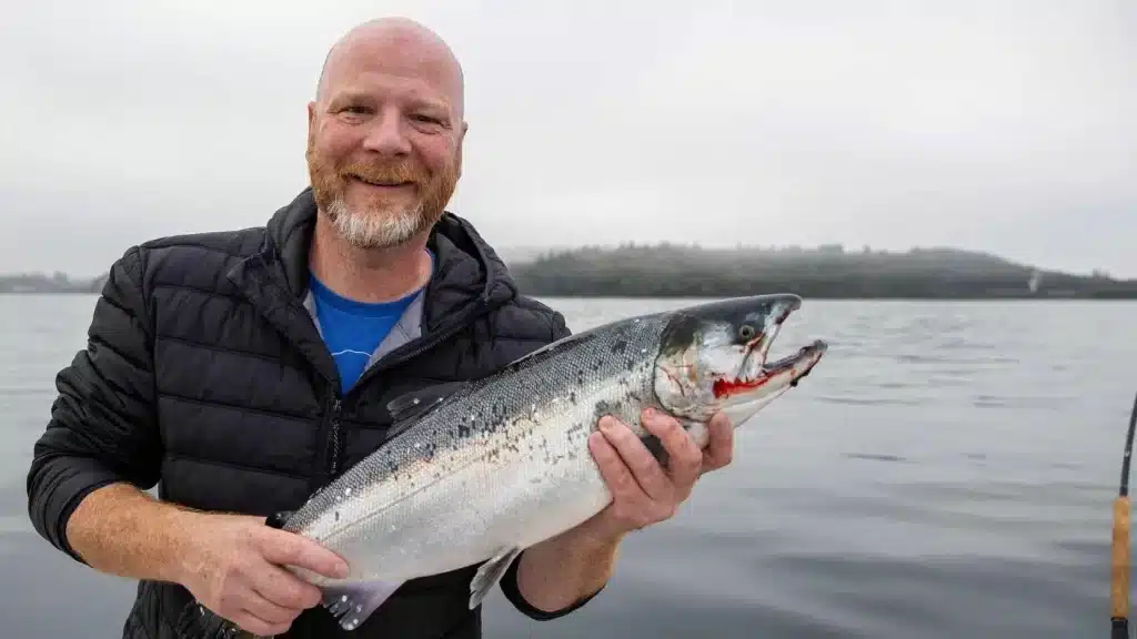 a man holding a coho salmon